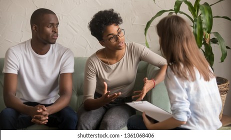 Unhappy jealous mixed-race wife talk to psychologist counselor complain on bad relationship with husband, african american family couple counseling have conversation about problem at therapy session