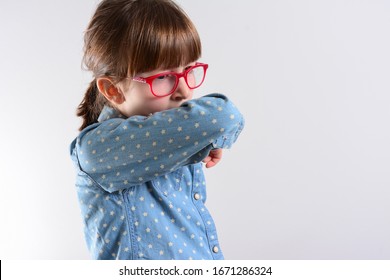 Unhappy Kid Cough Into Her Elbow, Not Her Hand. Small Girl Pull The Collar Of Her T-shirt Up To Cover Mouth When Coughing. Coughing Advice From Experts Who Seek To Minimize Risk Of Viral Transmission