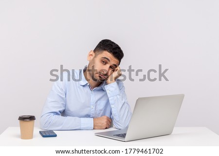 Unhappy lazy inefficient man employee sitting office workplace with laptop on desk, looking disinterested indifferent, apathy and lack of energy. indoor studio shot isolated on white background Сток-фото © 