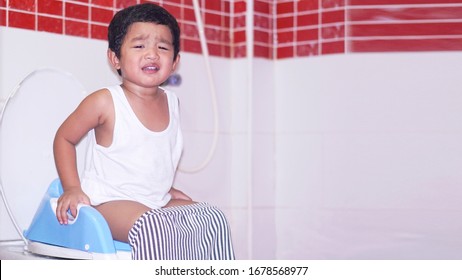 Unhappy Of Little Asian 2 Year Old Toddler Baby Boy Or Child Learn To Sitting On The Toilet Modern Style With A Kid In Bathroom. Asian Boy Cry Because Stomach Ache.