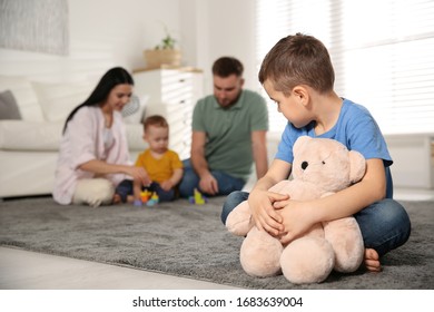 Unhappy Little Boy Feeling Jealous While Parents Spending Time With His Baby Brother At Home