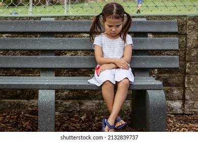 Unhappy Little Girl Sitting Alone Outside At School. 