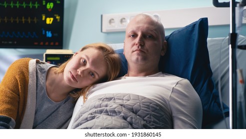 Unhappy Male Cancer Patient And Wife Looking At Camera Near Life Support Machine In Clinic Ward