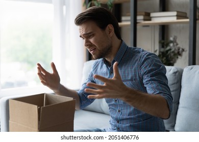 Unhappy man frustrated by wrong order online shopping or damaged package, bad delivery service, upset confused Caucasian customer opening unpacking parcel, cardboard box, sitting on couch at home