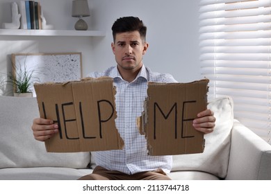 Unhappy Man With HELP ME Sign On Sofa Indoors