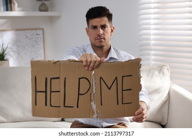 Unhappy Man With HELP ME Sign On Sofa Indoors