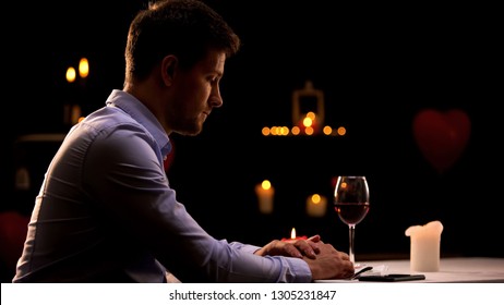 Unhappy Man Sitting Alone In Restaurant, Waiting For Woman, Unsuccessful Date