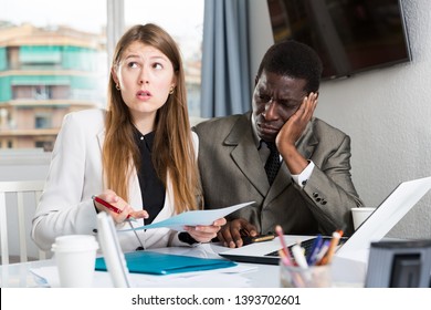 Unhappy managers working  with laptop and documents at table in office interior - Shutterstock ID 1393702601