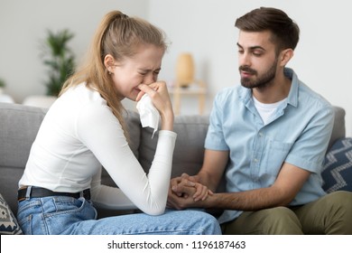 Unhappy Married Couple On Couch At Home. Wife Crying Husband Calms Her Quarrel Apologize. Interruption Of Unwanted Pregnancy Or Miscarriage. Friend Support Girlfriend After Break Up With A Loved One