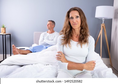 Unhappy Mature Couple Sitting On Bed In Bedroom - Powered by Shutterstock