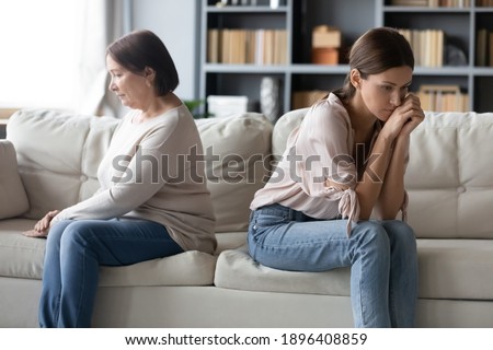 Unhappy mature mother and grownup daughter ignoring each other after quarrel, sitting on couch at home separately back to back, avoiding talking, two generations of women conflict concept Stock photo © 