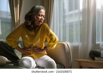 Unhappy Mature Woman Putting Hands On Belly, Suffering From  Stomach Ache, Caused By Indigestion Or Diarrhoea.