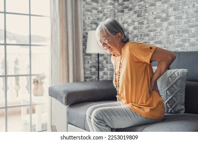 Unhappy mature woman touching back, feeling pain, sitting on couch in living room, unhealthy middle aged senior female suffering from backache, spinal problem, rubbing stiff muscles or kidney - Powered by Shutterstock