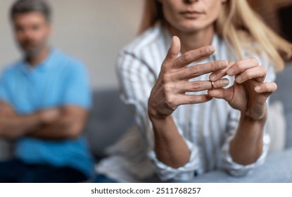 Unhappy middle aged european lady takes off ring, ignoring man during quarrel in living room interior, cropped. Relationship problems, divorce, scandal and breakup, emotions at home due covid-19 - Powered by Shutterstock