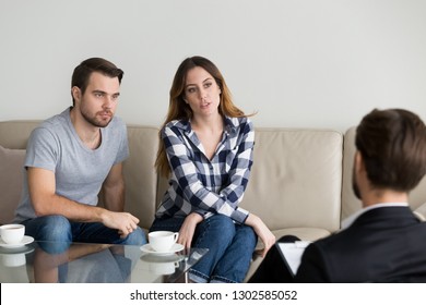 Unhappy Millennial Couple Talking To Psychologist Sitting On Couch Visiting Counselor Sharing Problems In Bad Relationships At Family Therapy Session, Marriage Counseling Psychotherapy Concept