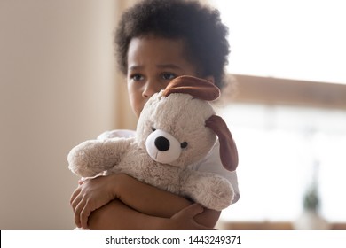Unhappy mixed race little boy stand hugging stuffed teddy bear feel lonely lacking attention or communication, hurt small biracial kid hold plush toy suffer from loneliness, need parents - Powered by Shutterstock
