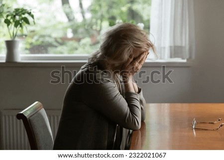 Unhappy old Caucasian woman sit at table at home cry feeling depressed sad suffer from life or health problems. Upset lonely mature female distressed with loneliness solitude, mourn yearn at home.