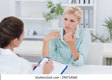 Unhappy Patient Speaking With Doctor In Medical Office