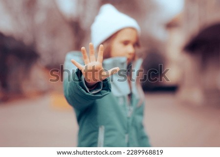 
Unhappy Preschool Little Girl Making a Stop Bullying Gesture. Desperate bullied child defending herself making halt sign
