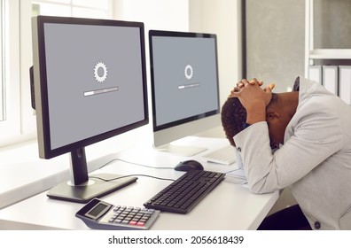Unhappy, sad businesswoman or professional accountant sitting in front of multiple desktop computers, holding head in despair, waiting for new operating system to load or software update to install