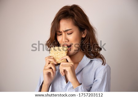 unhappy, sad girl eating instant noodle, concept of cheap budget fast food for jobless girl, unemployed people, month end, no money, no income, high sodium, excessive MSG intake