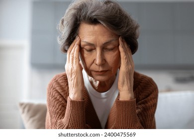 Unhappy senior woman suffering from headache or hypertension, massaging temples, feeling stressed, going through emotional crisis - Powered by Shutterstock