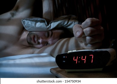 Unhappy Sleeping Man Smashing The Alarm Clock In The Morning (very Early).