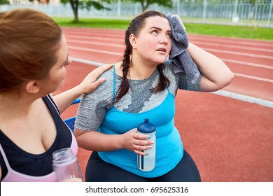 Unhappy And Sweaty Over-sized Female Drying Her Face With Towel While Another Woman Encouraging Her During Refreshment