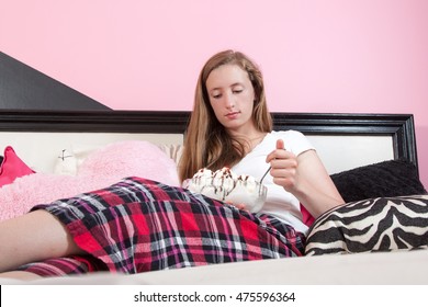 An Unhappy Teen Aged Girl Eating A Sundae On Her Bed In Her Room