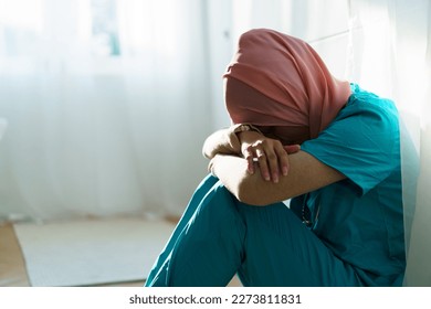 Unhappy - tired Muslim female surgeon doctor sitting on the floor in the hospital. Overworking problem and stress in medical staff concept. - Powered by Shutterstock