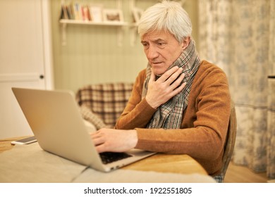 Unhappy Unwell 50 Year Old Man With Scarf Around His Neck Suffering From Influenza, Working From Home On Medical Leave, Coughing, Typing On Portable Computer, Making Contract. Technology And Health