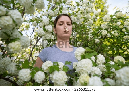 Unhappy woman with a clothespin on her nose on a walk in a blooming park. 