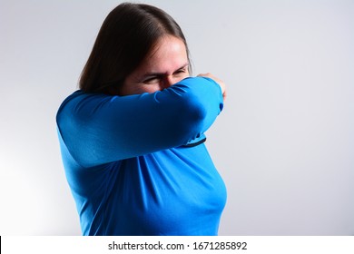 Unhappy Woman Cough Into Her Elbow, Not Her Hand. Woman Pull The Collar Of Her T-shirt Up To Cover Mouth When Coughing. Coughing Advice From Experts Who Seek To Minimize Risk Of Viral Transmission