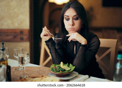 
Unhappy Woman Eating A Salad By Herself In A Restaurant
Sad Customer Displeased With Her Food Order And Portion Size
