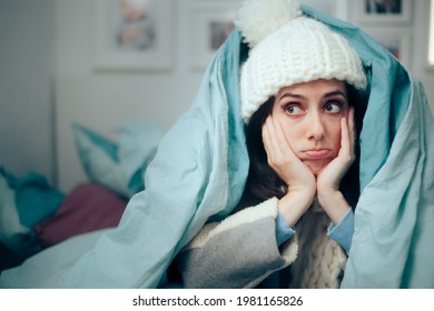 Unhappy Woman Feeling Cold Wearing Warm Winter Clothes Indoors. Sad Broke Poor Person Unable To Pay Electric Bill Suffering From Cold In Her Own Unheated Home During Winter
