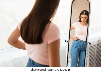 Unhappy Woman Gaining Excess Weight Touching Drooping Belly Standing At Mirror At Home. Unsuccessful Diet. Selective Focus - Shutterstock ID 1735304246