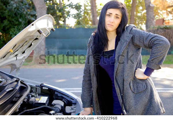 Unhappy woman looking\
broken engine of car