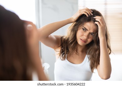 Unhappy Woman Looking At Hair Flakes Having Dandruff Problem Indoor