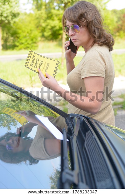 Unhappy\
woman showing parking ticket. Focus on\
ticet