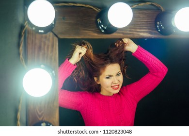 Unhappy Woman Sits In A Beauty Salon In Front Of A Mirror And Looks At Bad Hair . The Concept Of Painting And Hair Cutting In A Bad Hair Salon