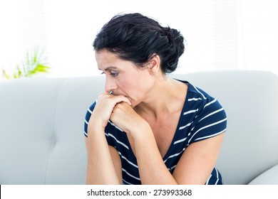 Unhappy woman sitting on the couch on white background