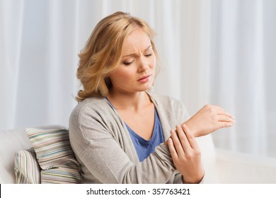 Unhappy Woman Suffering From Pain In Hand At Home