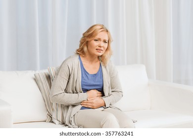 unhappy woman suffering from stomach ache at home - Shutterstock ID 357763241