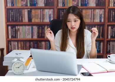 Unhappy young asian female worker look at laptop screen shocked by operational problems. Frustrated woman confused surprised by unexpected error on computer device.