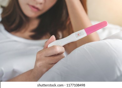 Unhappy young asian woman holding pregnancy test showing a negative result, Selective focus and copy space, Wellness and healthy concept, Infertility problem.