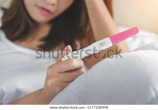 Unhappy young asian woman holding\
pregnancy test showing a negative result, Selective focus and copy\
space, Wellness and healthy concept, Infertility\
problem.
