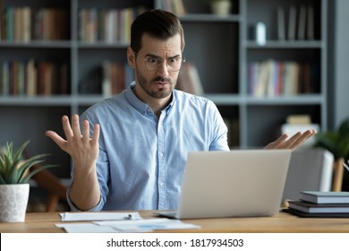 Unhappy young Caucasian male worker in glasses look at laptop screen shocked by gadget breakdown or operational problems. Frustrated man confused surprised by unexpected error on computer device. - Shutterstock ID 1817934503