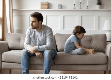 Unhappy young Caucasian man father and little 6s son sit separate ignore each other after family fight. Upset stubborn dad and small boy child avoid talking having quarrel. Generation gap concept. - Powered by Shutterstock