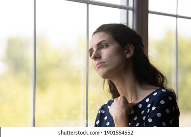 Unhappy young Caucasian woman look in window distance mourn or yearn, feel sad lonely at home. Upset distressed millennial female loner quarantine alone indoors. Solitude, loneliness concept.