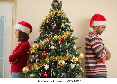 Unhappy Young Couple Standing Back To Back Next To The Christmas Tree